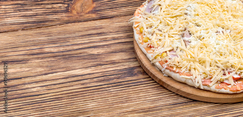 Raw homemade pizza on the wooden table.