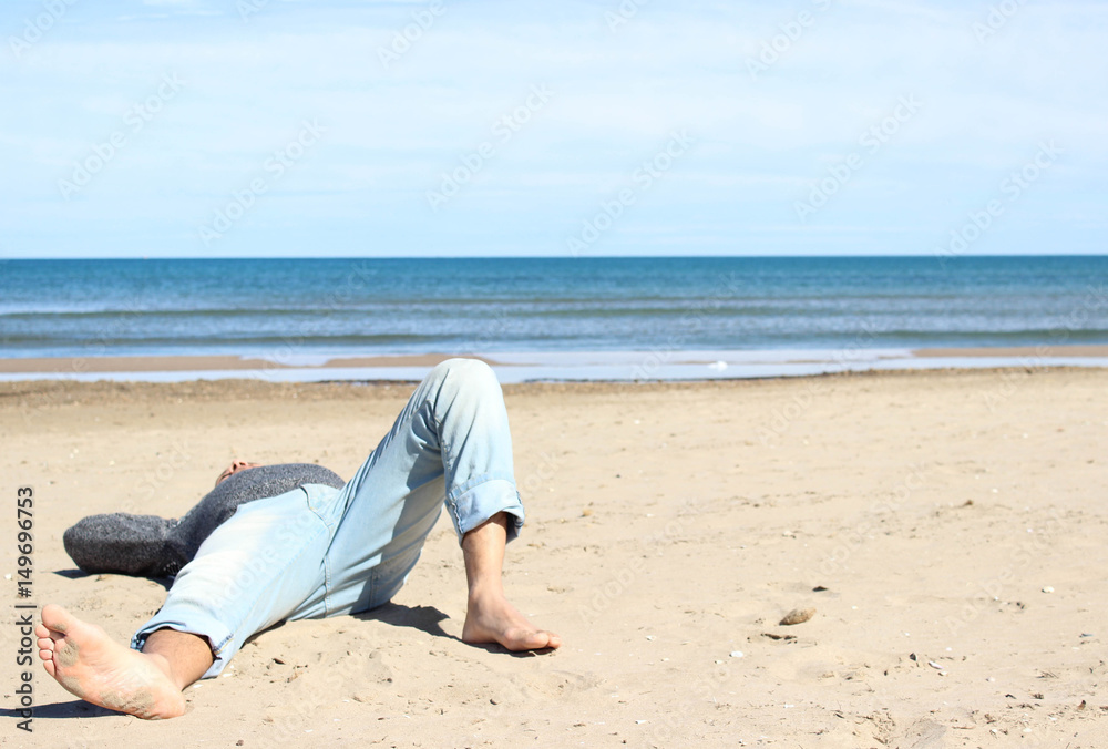 Young man laying at the beach of Valencia in a sunny summer day