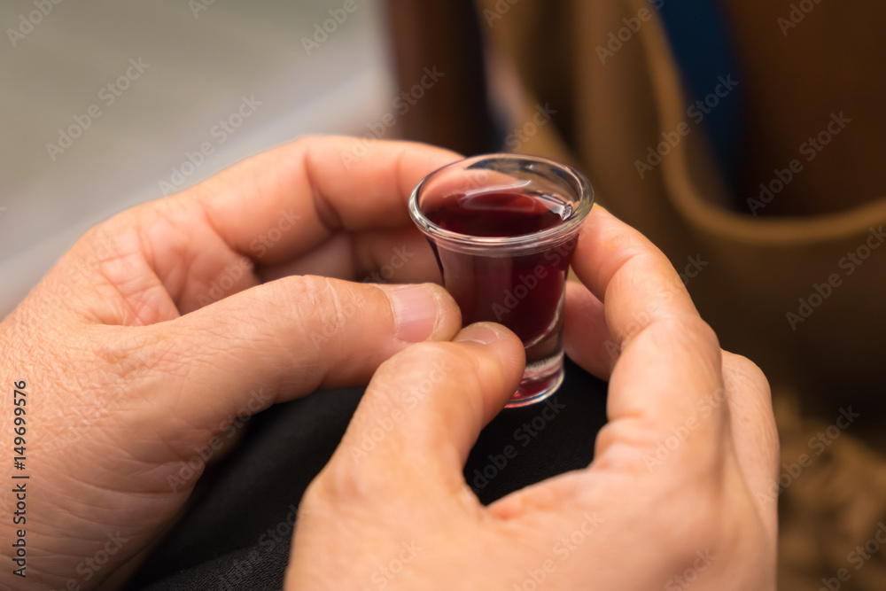 A lady's hands hold a red wine cup in Holy Communion. A lady's hands hold a red wine cup in Holy Communion.