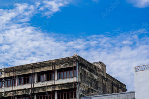 Rooftop of neglected and unoccupied old building with clear blue sky behind