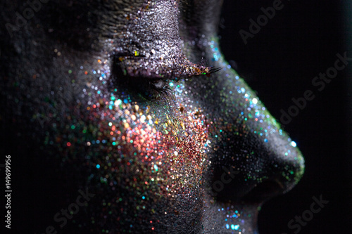 Portrait of beautiful woman with sparkles on her face. Fashion model with colorful make-up