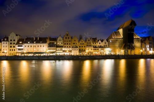Long Embankment and Motlawa River in the Old Town of Gdansk, Poland at night. Medieval port Crane - the most characteristic symbol of Gdansk on the right.