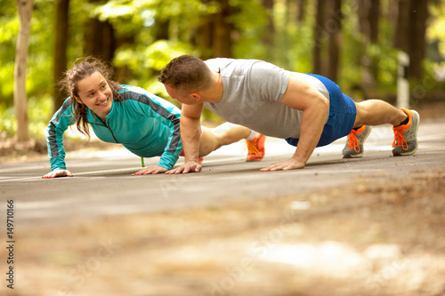 Couple doing push-ups at the park.Workout outdoors.