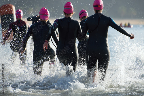 Fotografie Group triathlon participants running into the water for swim portion of race,spl