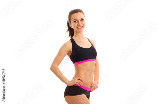 beautiful smiling young girl with slim body keeps a hand on the side and looking directly