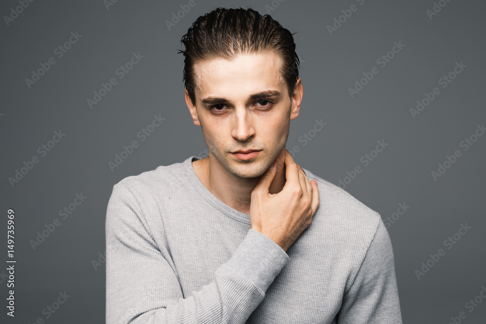 Portrait of a smart serious handsome young man standing against grey background