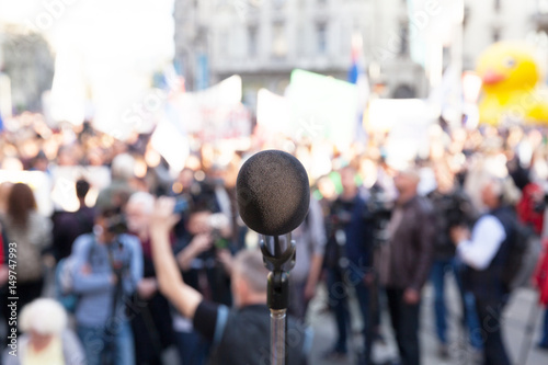 Protest. Political rally. Demonstration. Microphone in focus, blurred crowd in background.