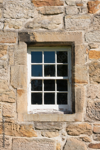 old style paned glass window set in stone wall