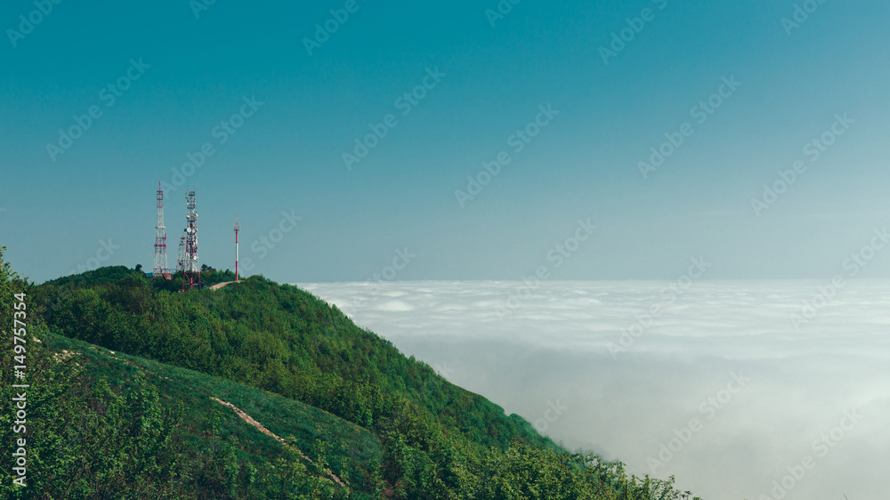 Telecommunication towers on top of a mountain against a background of clouds and fog. Mountain landscape. Gelendzhik, North Caucasus, Russia - obrazy, fototapety, plakaty 
