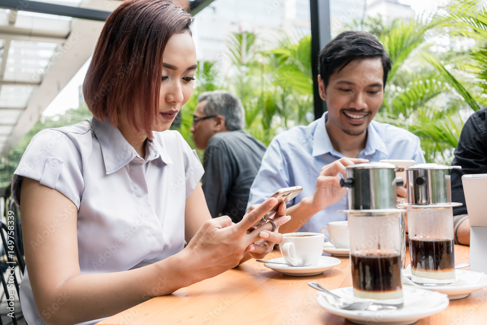 Three friends using devices connected to the wireless internet network of a coffee shop