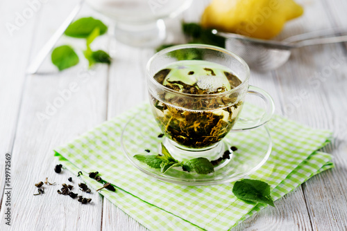 Drinks, green leaf tea with sugar, mint and lemon on a white rustic wooden background 