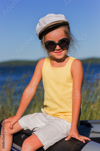 Girl in sailor cap on the lake in summer sunny day on vacation