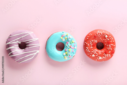 Tasty donuts with sprinkles on paper background