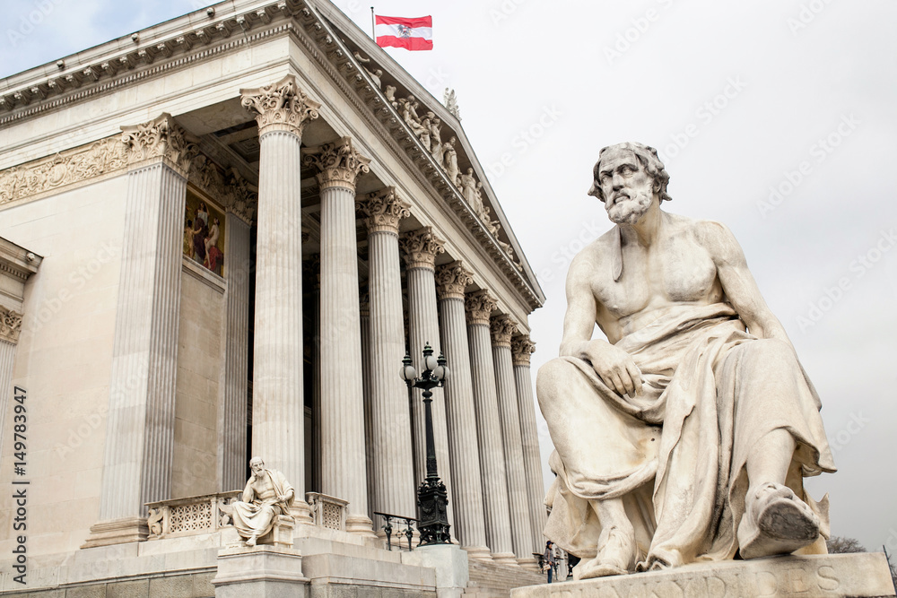 main entrance of Austrian parliament building in Greek style with statues of philosophers and white columns with famous Pallas Athena fountain and in Vienna