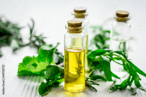 organic oil in bottle with rosemary and mint on light table background