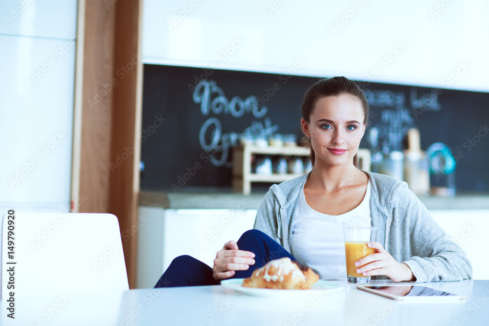 Young woman with orange juice and tablet in kitchen Young woman with orange juice and tablet in kitchen