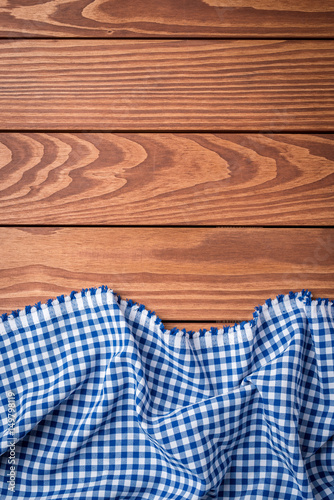Blue checkered tablecloth on an old wooden table. Top view