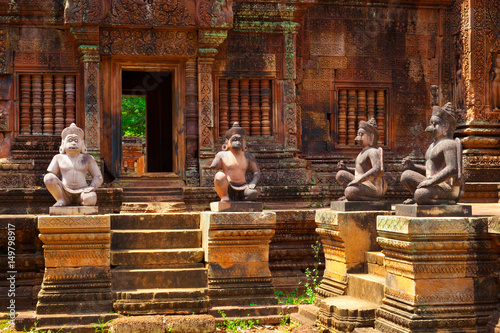 Banteay Srei temple, Angkor, Cambodia. Statues of human figures with animal heads, guardians at the ancient Khmer temple built in red sandstone