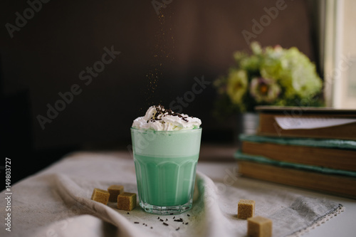 Green mint coffee with with cream and colorful decoration on dark background. Milk shake, cocktaill, frappuccino.  Unicorn coffee, unicorn food. photo