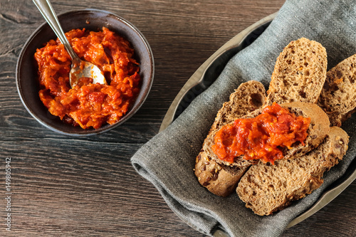 A bowl of red pepper and walnut dip served with bread