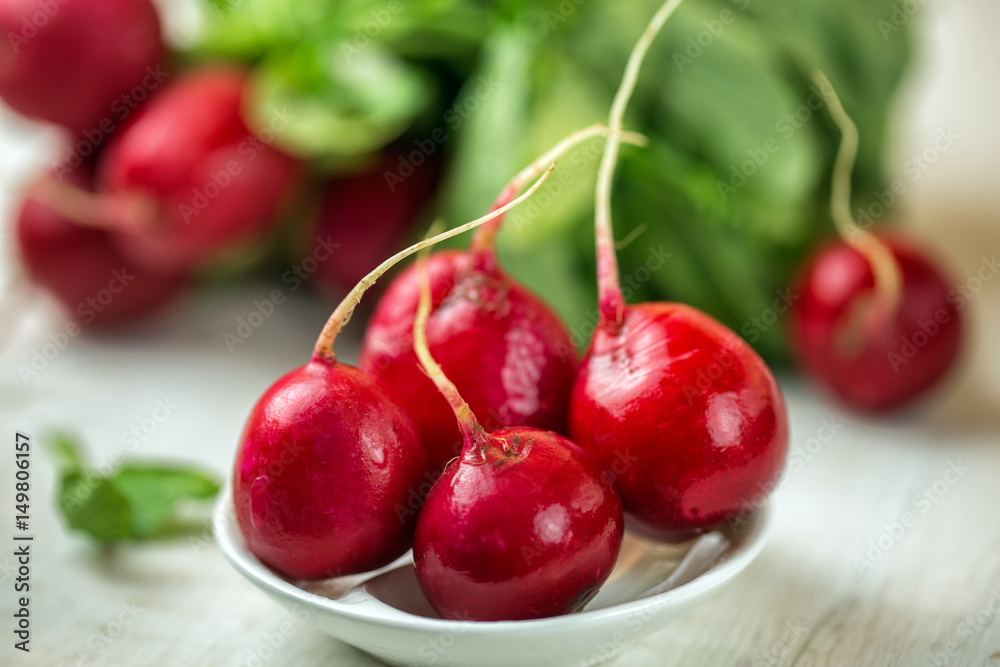 Red radishes in bowl on wooden table. Vegetable of cabbage family. Red radishes in bowl on wooden table. Vegetable of cabbage family.