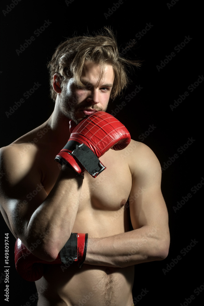 Boxer thinks or dreams. Portrait of boxer posing in studio in red boxing gloves.
