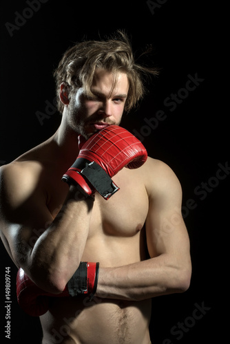 Boxer thinks or dreams. Portrait of boxer posing in studio in red boxing gloves. © Tverdokhlib