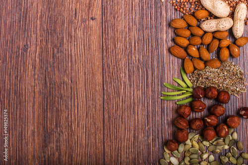 Assorted nuts on wooden surface. peanuts, almonds, hazelnuts, pumpkin seeds, walnuts, rice, buckwheat. Top view with copy space.