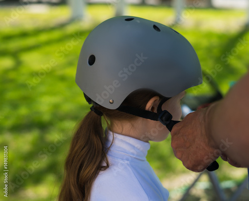 Father putting on safety helmet to his small daughter for riding