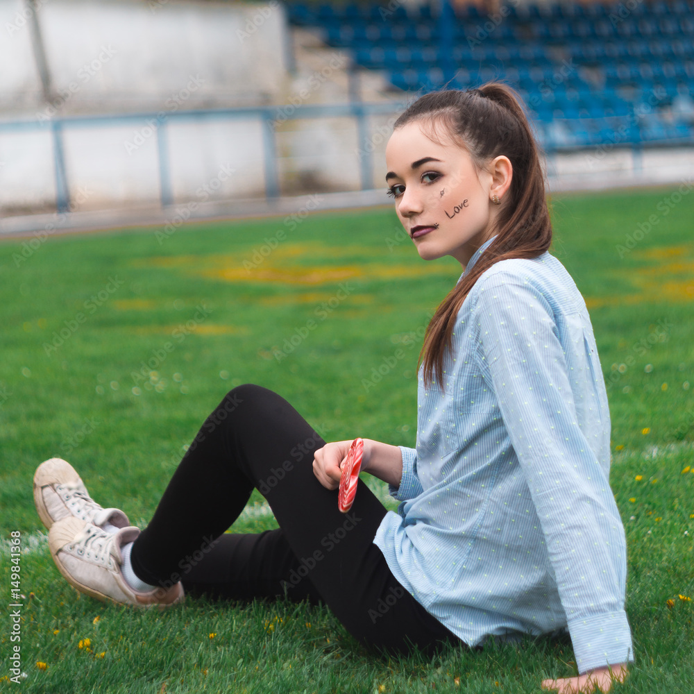 Beautiful and happy girl in the blue shirt with lollipop stadium Beautiful and happy girl in the blue shirt with lollipop stadium