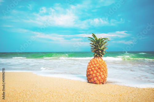 Fototapeta Naklejka Na Ścianę i Meble -  Ripe pineapples on the sandy tropical beach with clear blue sky. Leisure in summer and Summer vacation concept. vintage color tone.