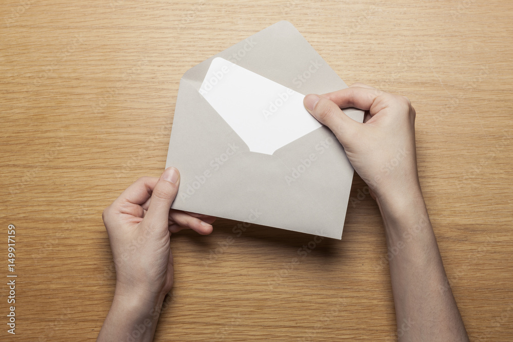 woman hand hold a envelope and letter on the wood table.
