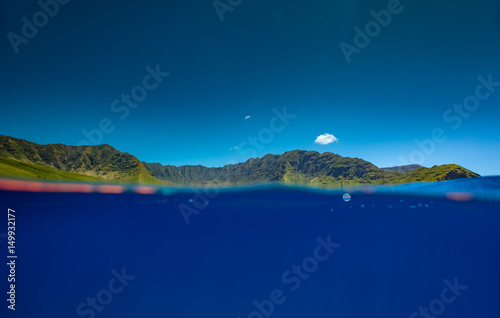Mountain valley in ocean blue water. Tropical landscape splitted by water line.