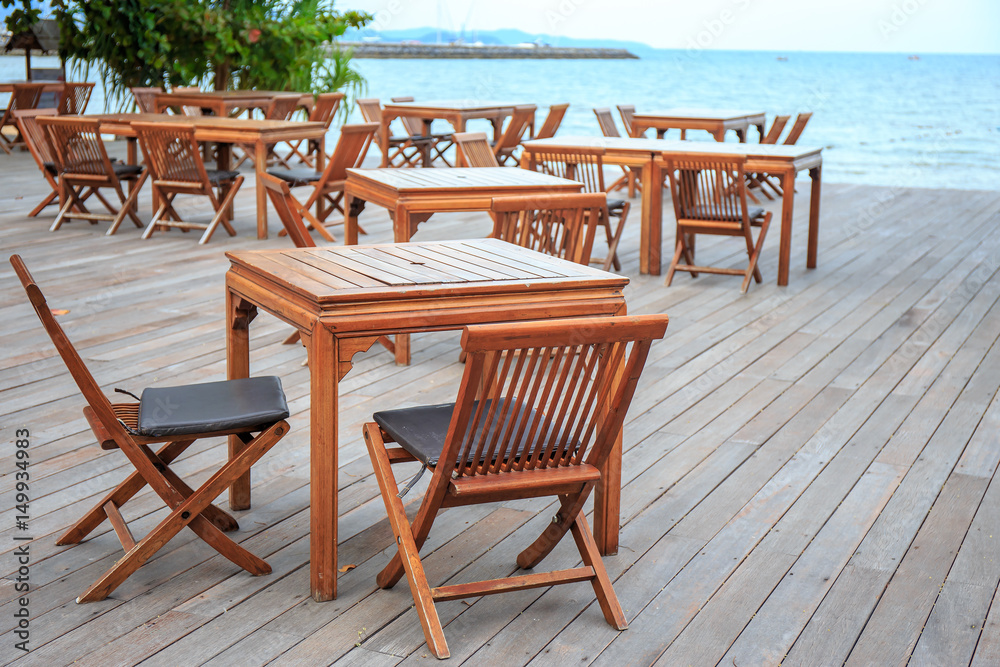 Wooden chairs and table of restaurant overlooking near the sea beach.