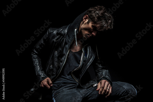 side view of a man wearing hoodie and leather jacket