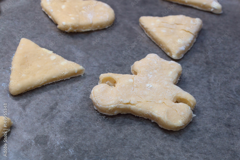 Cookie dough in different shapes lies on the baking sheet. Cookie dough in different shapes lies on the baking sheet.