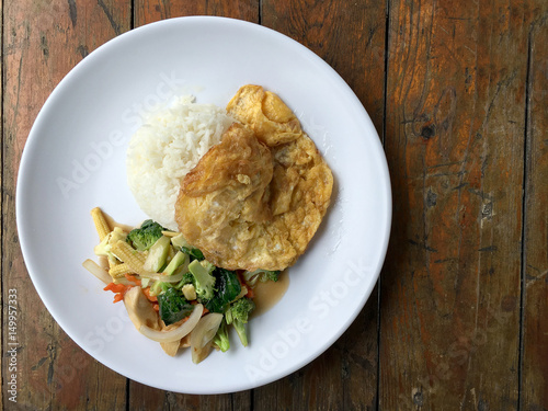 Vegetable stir fry with Omelette in a white plate on wooden background. Thai style food. Vegetarian Food