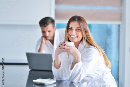 Happy woman in the kitchen reading he news on her laptop