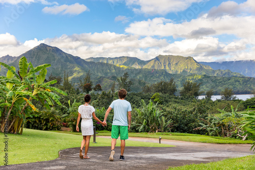 Couple tourists walking on Hawaii vacation. Two young people relaxing in Hanalei Bay resort in Kauai, Hawaii travel beach destination with Kauai mountains in the background. photo