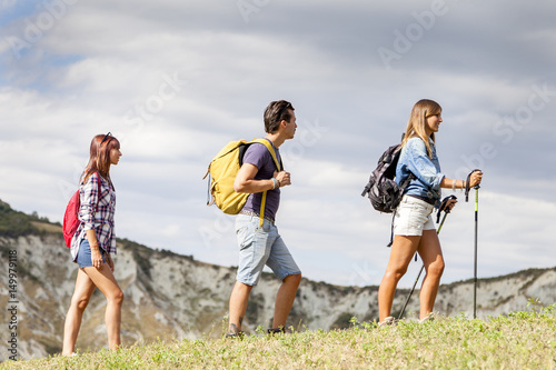 group of young hikers walking toward the horizon over the mountain