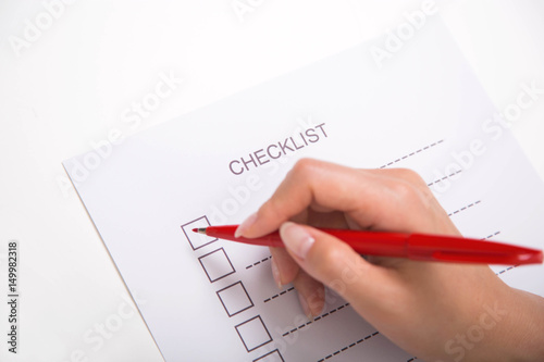 Close-up of hand marking on checklist with red pen