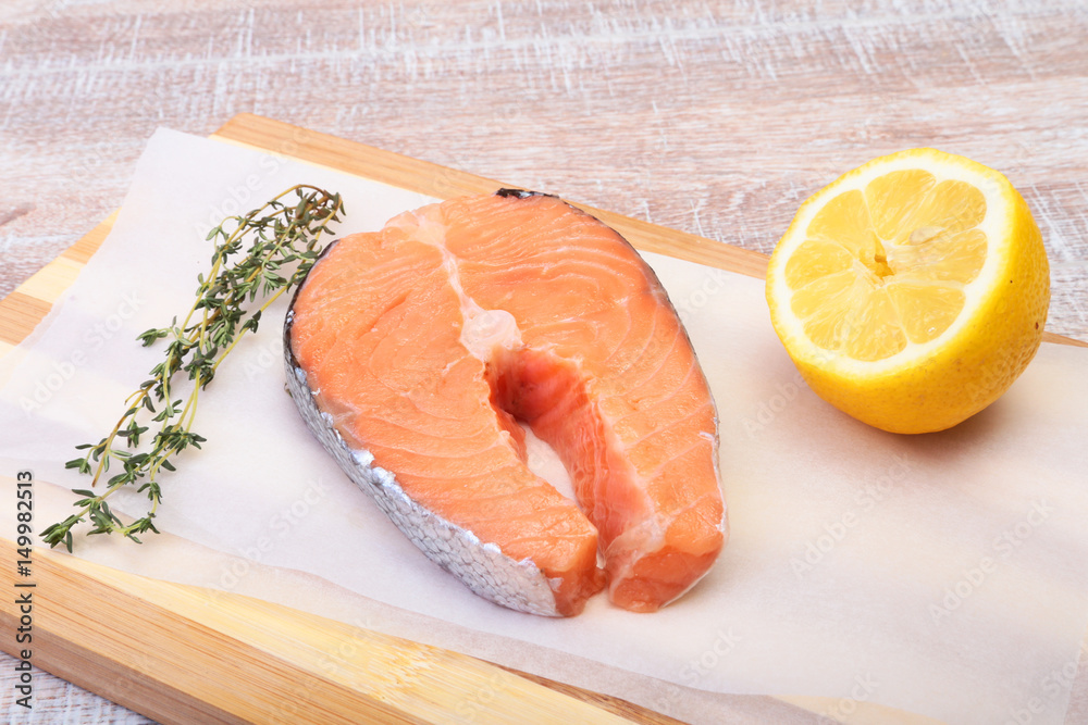 fresh raw salmon with spices and lemon on wooden cutting board. ready for cookin fresh raw salmon with spices and lemon on wooden cutting board. ready for cookin