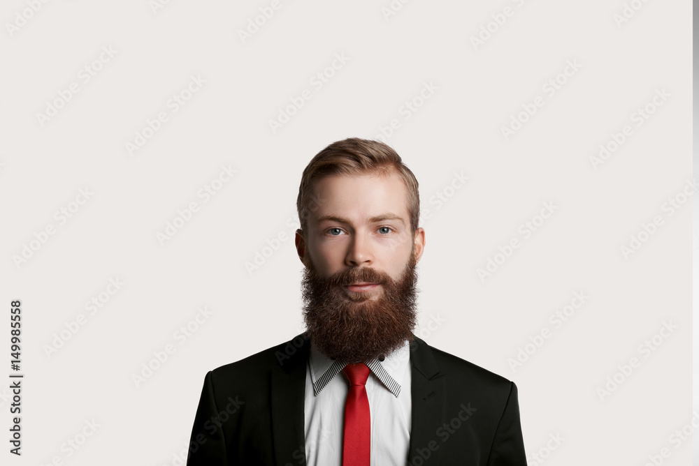 Handsome bearded top manager in black suit and red tie. Quiet emotion on man face. Guy keep tranquility and look to the camera. Big boss have speech for customers about big sale. Handsome bearded top manager in black suit and red tie. Quiet emotion on man face. Guy keep tranquility and look to the camera. Big boss have speech for customers about big sale.