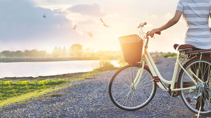 woman standing with vintage bicycle, relaxing in summer sunset nature rural with flying birds