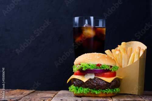 Burger menu with french fries and soft drink on wooden table