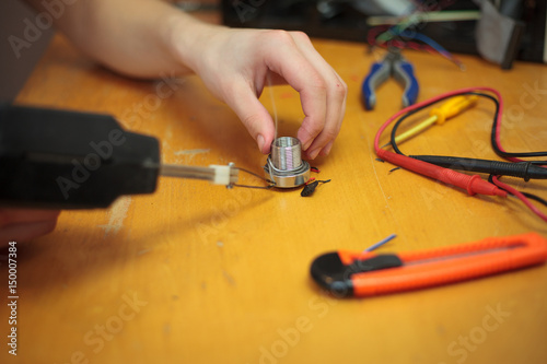 Wallpaper Mural Young man hands gathering tin by black solder and preparing for a soldering (color toned image) Torontodigital.ca