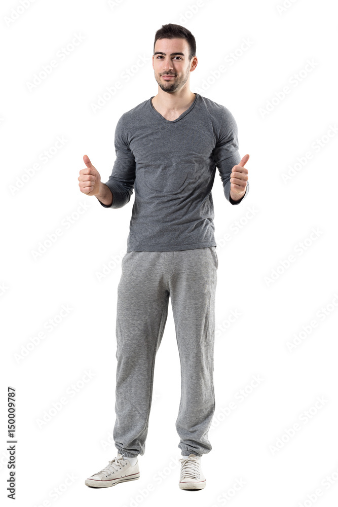 Happy young sporty fit man showing thumbs up gesture smiling at camera. Full body length portrait isolated on white studio background. Happy young sporty fit man showing thumbs up gesture smiling at camera. Full body length portrait isolated on white studio background.