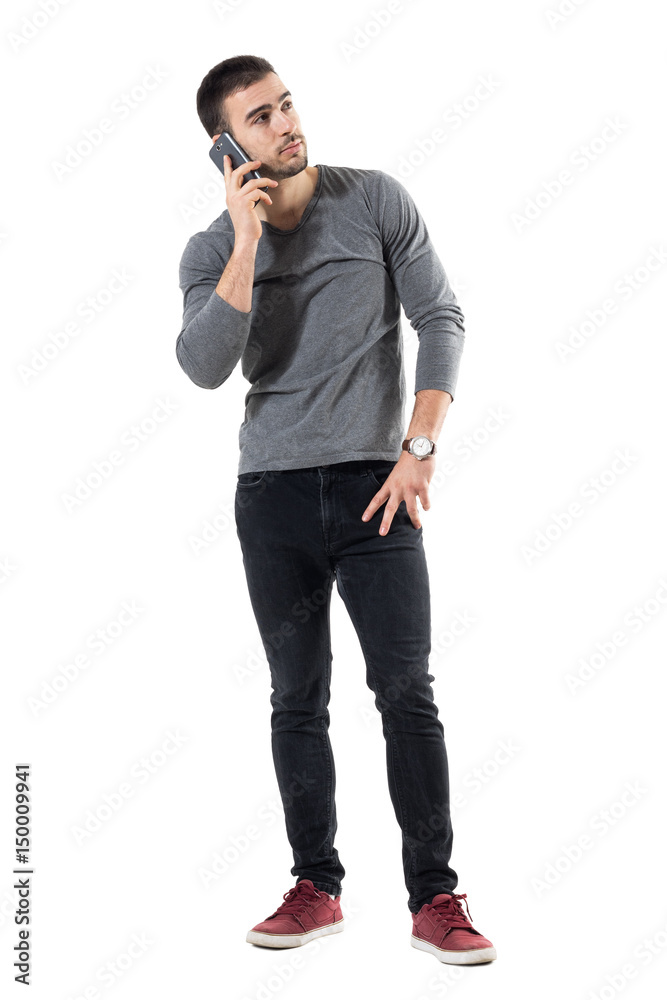 Young trendy casual man talking on the mobile phone looking up. Full body length portrait isolated on white studio background. Young trendy casual man talking on the mobile phone looking up. Full body length portrait isolated on white studio background.