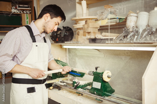 Young turner engages in wood carving on lathe for wood