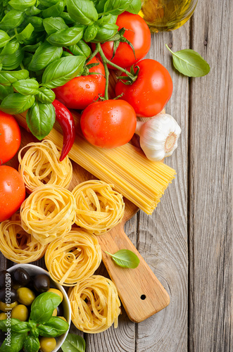 Pasta, vegetables, herbs and spices for Italian food on wooden background, top view